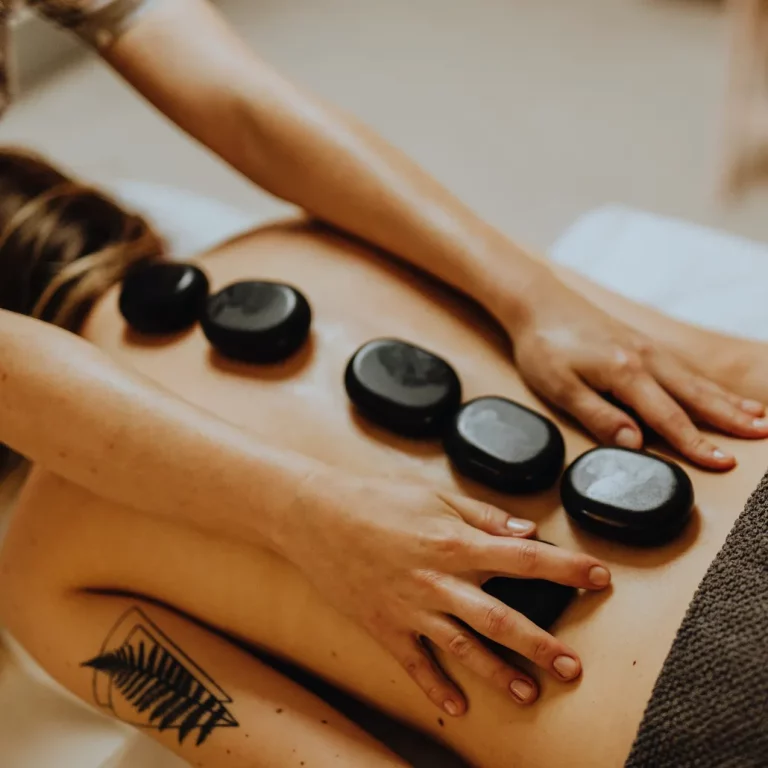 behandling hot stone massage, närbild på en kvinnas rygg där det ligger flera stenar på rad